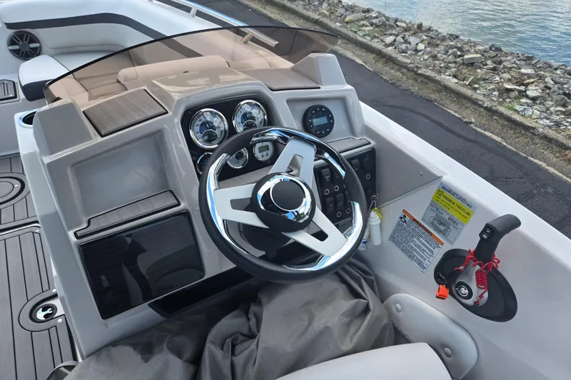 Slide: The Image of 2024 Starcraft SVX 191 OB boat dashboard with steering wheel and controls by the water. - 10