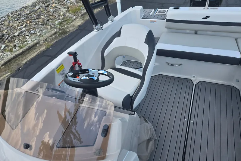 Slide: The Image of 2024 Starcraft SVX 191 OB boat interior with steering wheel and seating, dockside view. - 19