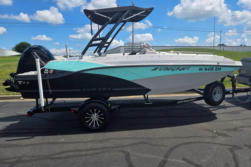 Slide: The Image of 2024 Starcraft SVX 191 OB boat on trailer, parked outdoors under blue sky. - 4