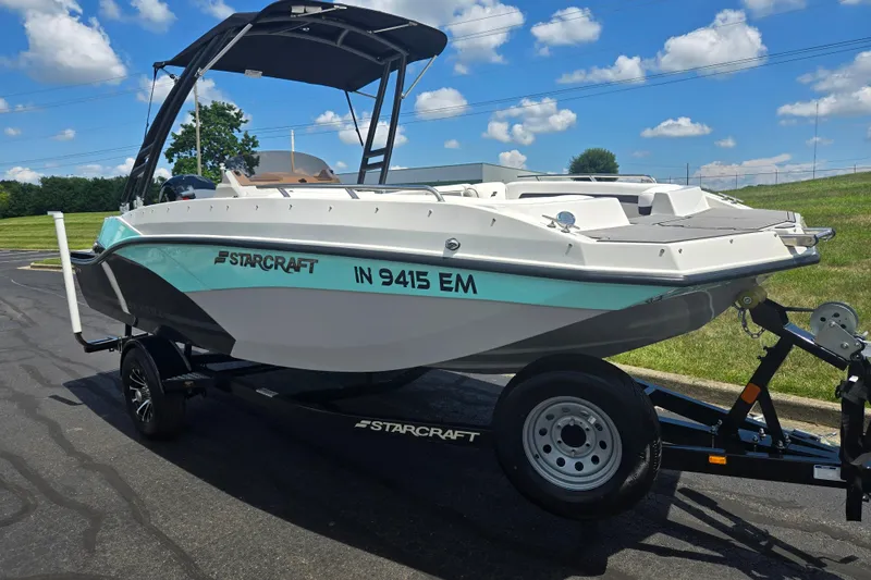 Slide: The Image of 2024 Starcraft SVX 191 OB boat on trailer, parked outdoors under a blue sky. - 5
