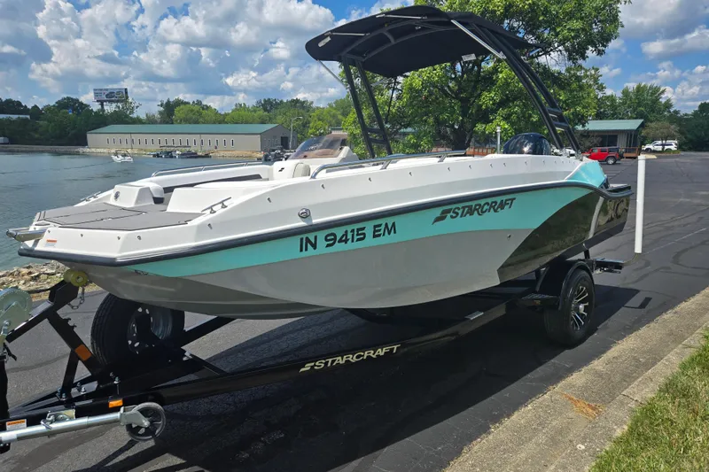 Slide: The Image of 2024 Starcraft SVX 191 OB boat on trailer by a lakeside, under a cloudy sky. - 7
