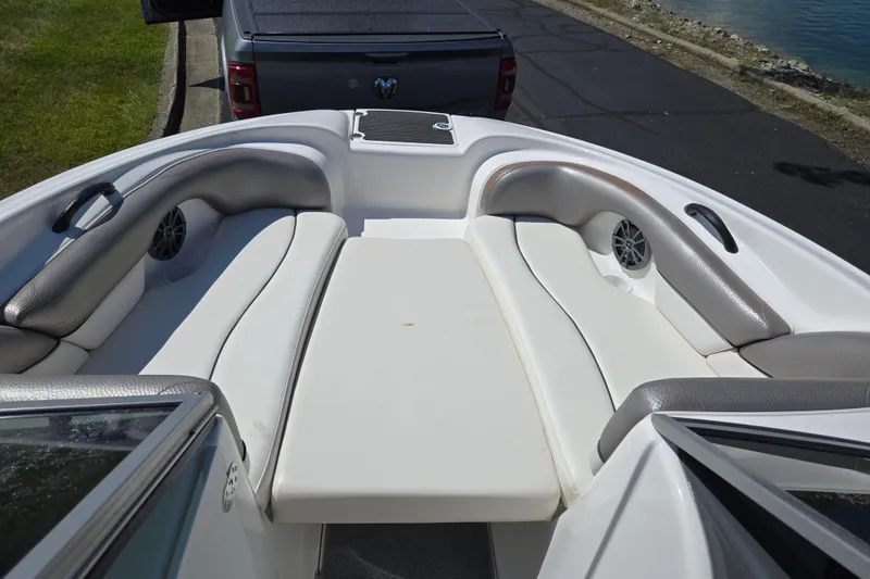 Slide: The Image of 2011 Yamaha AR210 boat interior with cushioned seating and speakers, parked near water. - 17