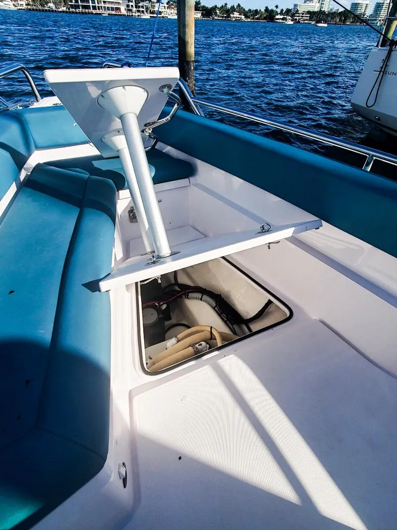Slide: The Image of 2021 Axopar 28 CABIN boat interior with open storage compartment, blue seating, and water view. - 22