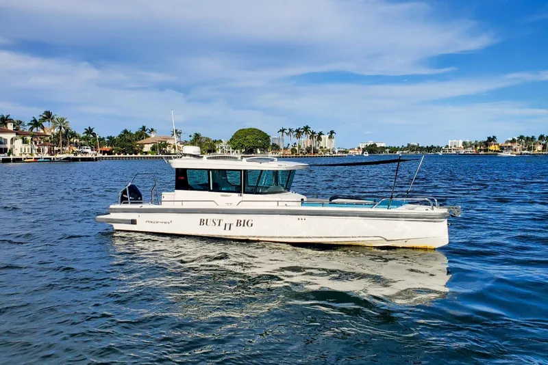 Slide: The Image of 2021 Axopar 28 CABIN boat on a sunny waterfront with palm trees. - 27