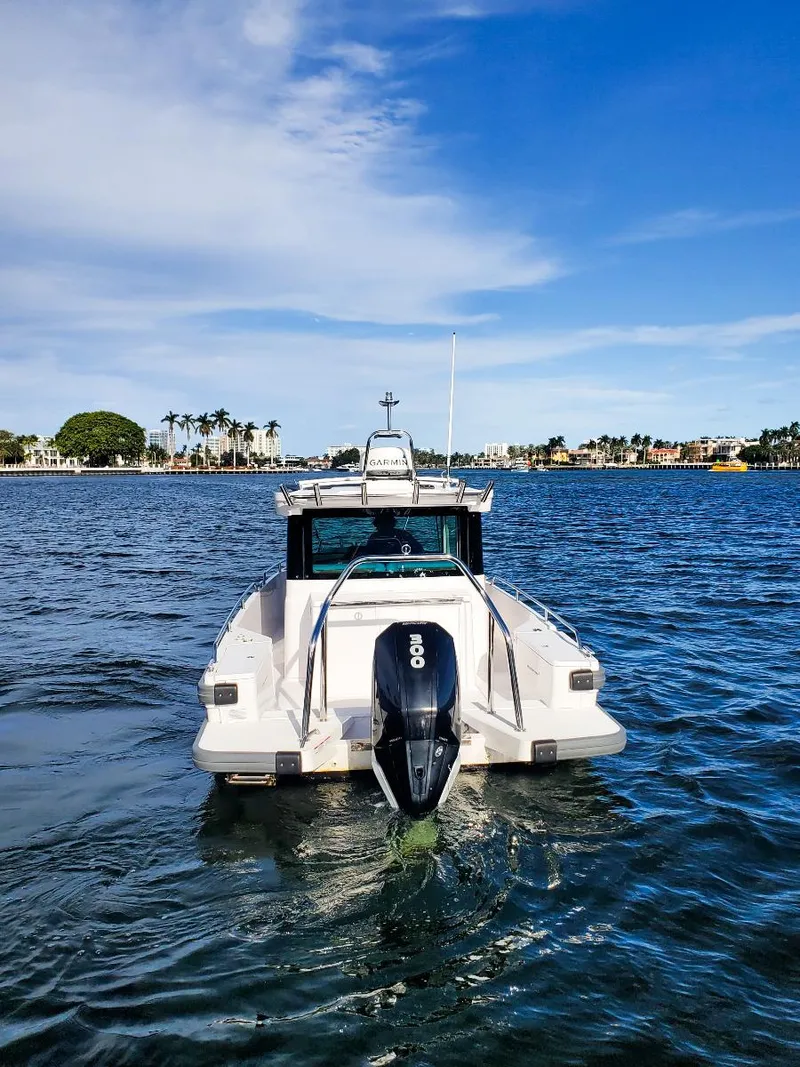 Slide: The Image of 2021 Axopar 28 CABIN boat on water, rear view, clear sky, coastal background. - 7