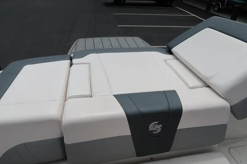 Slide: The Image of 2020 Chaparral 21 Surf boat seating, featuring white and gray upholstery in a parking lot. - 3