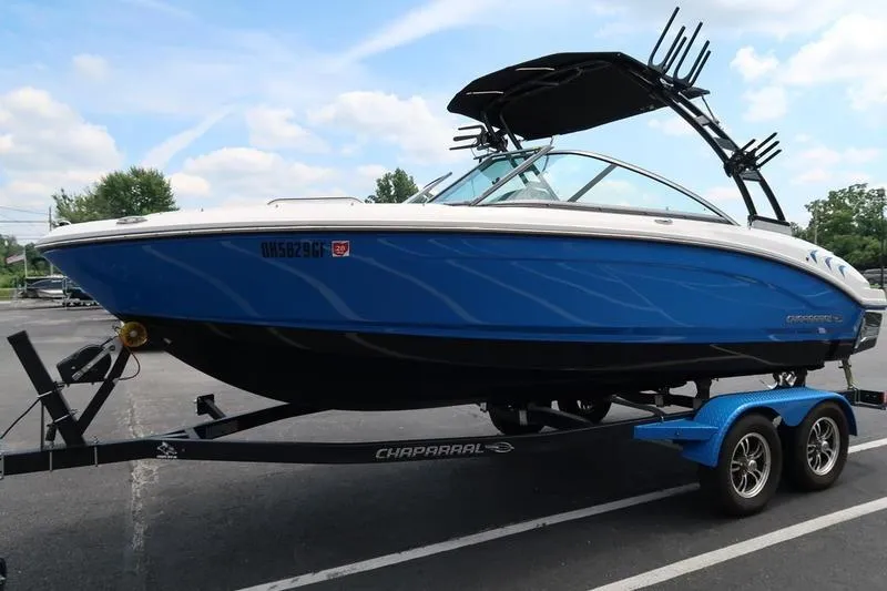 Slide: The Image of 2020 Chaparral 21 Surf boat on trailer, blue hull, parked outdoors. - 4