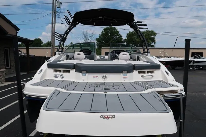 Slide: The Image of 2020 Chaparral 21 Surf boat with spacious deck and seating, parked outdoors. - 5