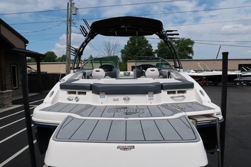 Slide: The Image of 2020 Chaparral 21 Surf boat with spacious deck and seating, parked outdoors. - 8