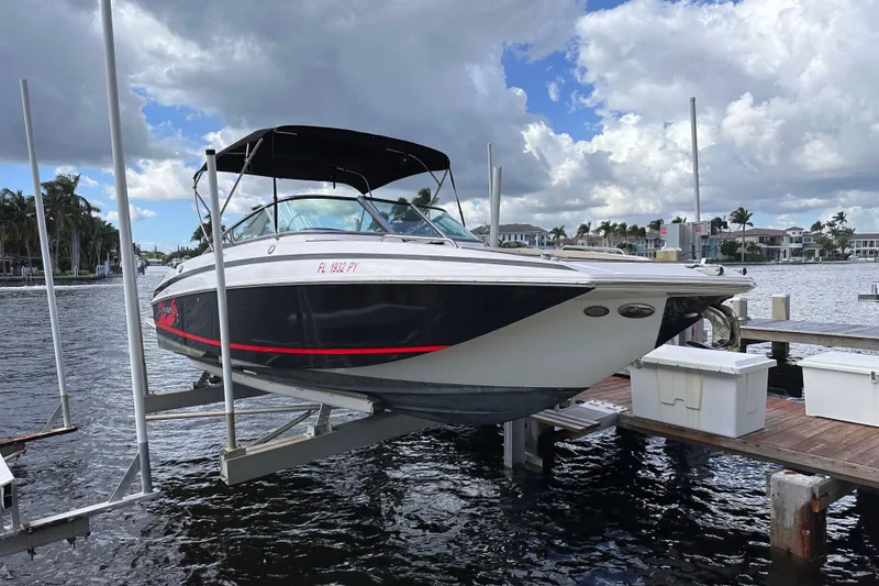 The Image of 2015 Regal 27 FasDeck boat on lift by waterfront dock, under cloudy sky. - 0