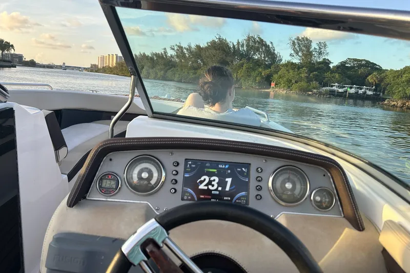 Slide: The Image of Cockpit view of a 2015 Regal 27 FasDeck boat cruising on a scenic waterway. - 13