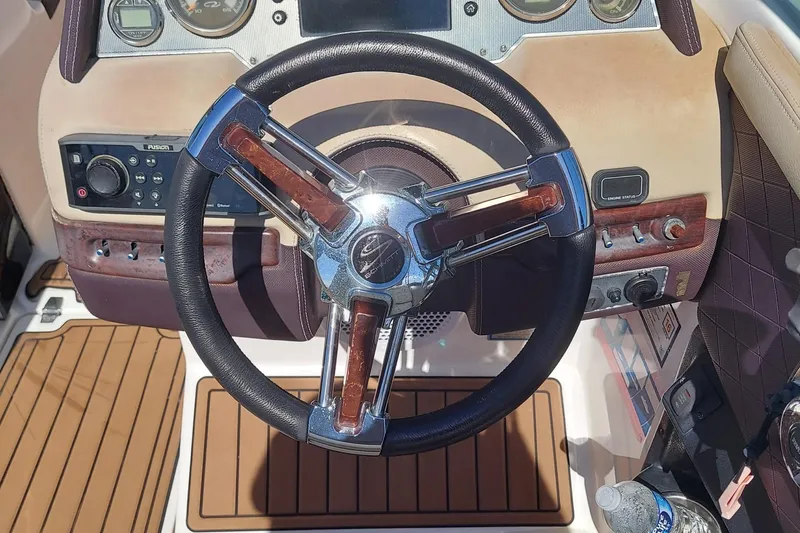 Slide: The Image of Steering wheel of a 2015 Regal 27 FasDeck boat with wood accents and control panel. - 21