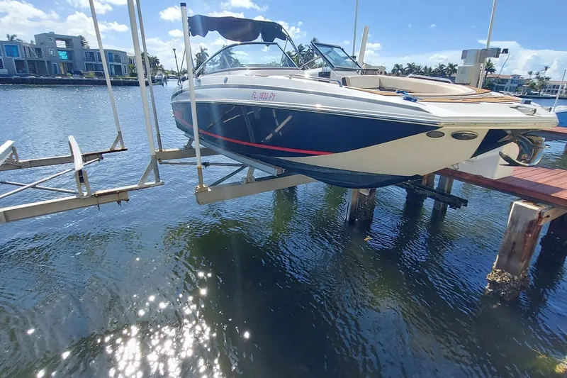 Slide: The Image of 2015 Regal 27 FasDeck boat on lift, docked by waterfront homes under sunny skies. - 23