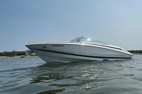 Slide: The Image of 2003 Regal 2200 Bowrider boat on calm water under clear sky. - 2