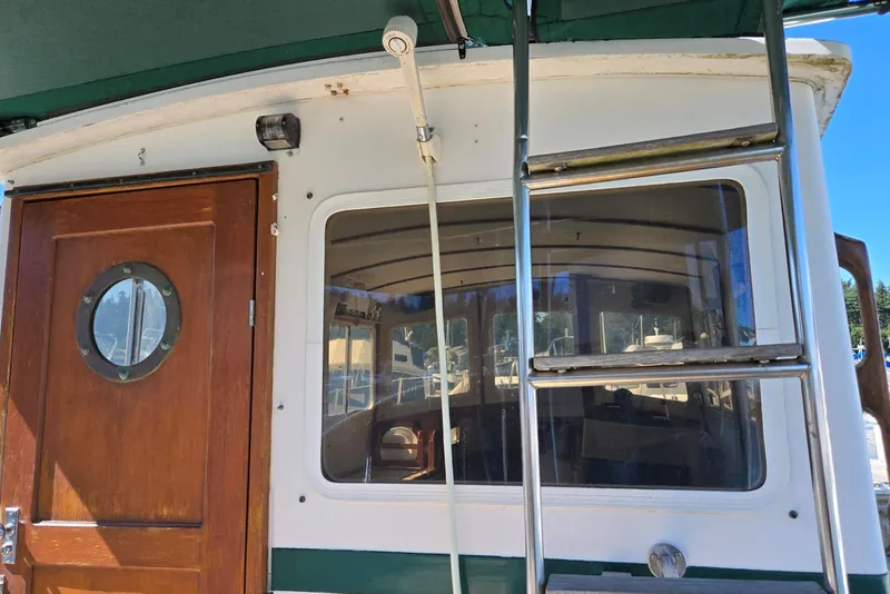 Slide: The Image of 1973 Willard Marine Vega Nomad Flybridge with wooden door and ladder, docked outdoors. - 13