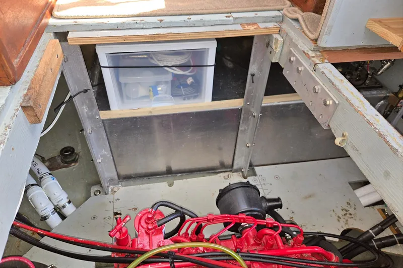 Slide: The Image of Engine compartment of 1973 Willard Marine Vega Nomad Flybridge, featuring red engine and storage box. - 31