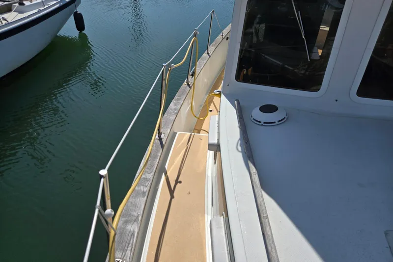 Slide: The Image of 1973 Willard Marine Vega Nomad Flybridge boat deck with railing, docked on calm water. - 9