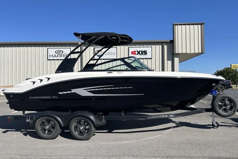 The Image of 2026 Chaparral 21 SSi boat on trailer, parked outside dealership under clear blue sky. - 0