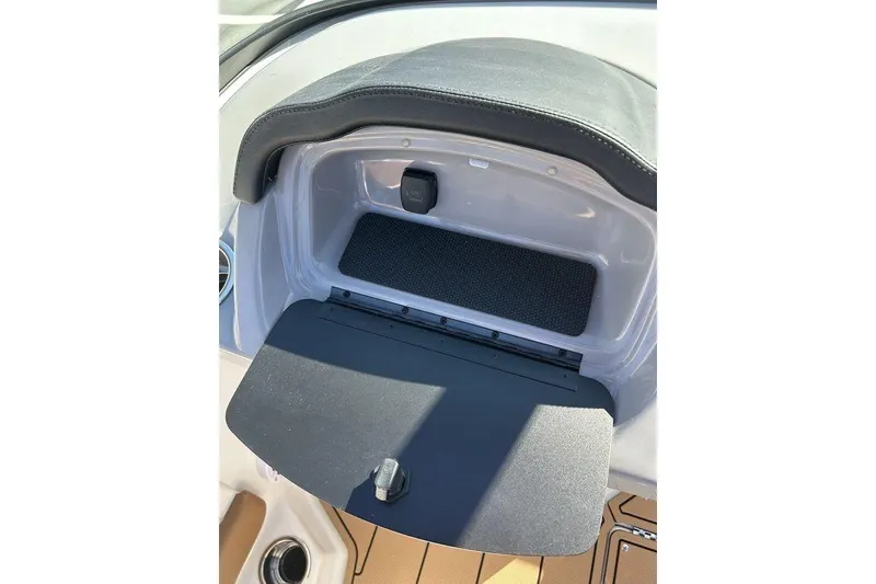 Slide: The Image of 2026 Chaparral 21 SSi boat dashboard storage compartment with open lid and black interior. - 8