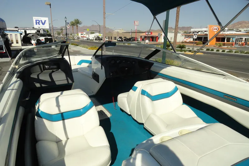 Slide: The Image of 1995 Wellcraft Eclipse 196 S boat interior with white and blue seating, parked near roadside. - 7
