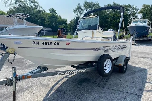 The Image of 2015 Triumph 170 CC boat on trailer, parked outdoors, with visible registration number. - 0