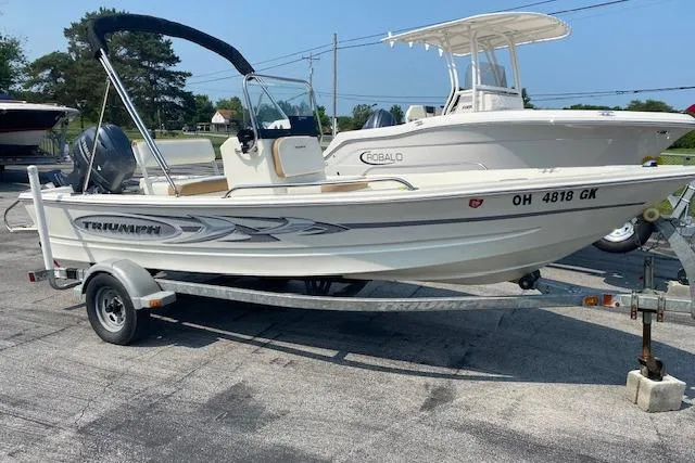 Slide: The Image of 2015 Triumph 170 CC boat on trailer, parked outdoors, with another boat in the background. - 2