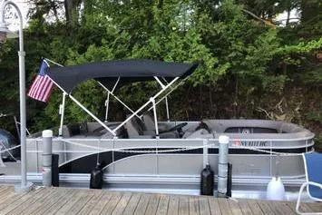 Slide: The Image of 2019 Bennington 22 SCWXP pontoon boat docked with canopy and American flag. - 13
