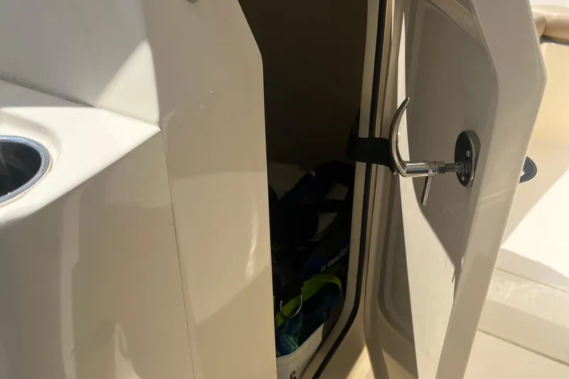 Slide: The Image of 2024 Scout 240 Dorado boat storage compartment with open door and latch. - 13