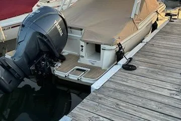 Slide: The Image of 2024 Scout 240 Dorado boat docked, covered, with Yamaha outboard motor. - 2