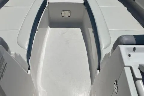 Slide: The Image of 2019 Chaparral 250 Suncoast boat interior with white seating and storage compartment. - 14