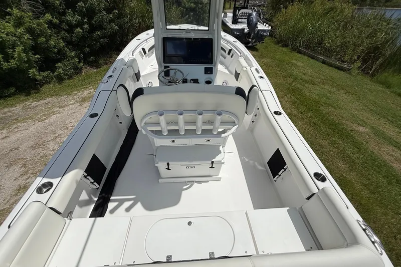 Slide: The Image of 2026 Tidewater 232 LXF boat interior with helm, seating, and lush greenery background. - 12