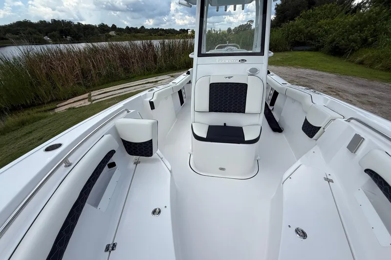 Slide: The Image of 2026 Tidewater 232 LXF boat interior with seating, near a serene lake and lush greenery. - 19