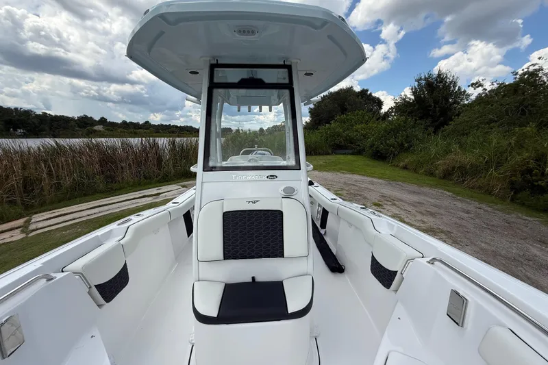 Slide: The Image of 2026 Tidewater 232 LXF boat interior with seating, under a cloudy sky by a lake. - 20