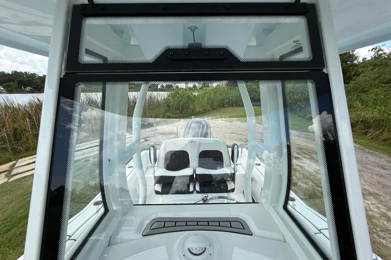 Slide: The Image of 2026 Tidewater 232 LXF boat interior view through windshield, showcasing seating and console. - 21