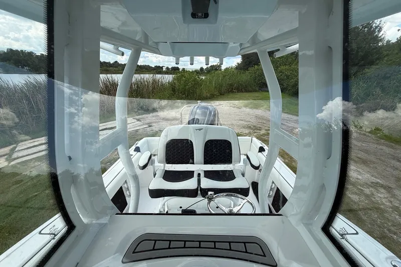 Slide: The Image of 2026 Tidewater 232 LXF boat interior with seating and steering wheel, near a lake. - 22