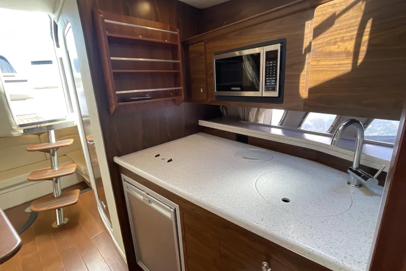 Slide: The Image of 2017 Rinker EX 370 cabin interior with striped bedding and wall-mounted TV. - 30