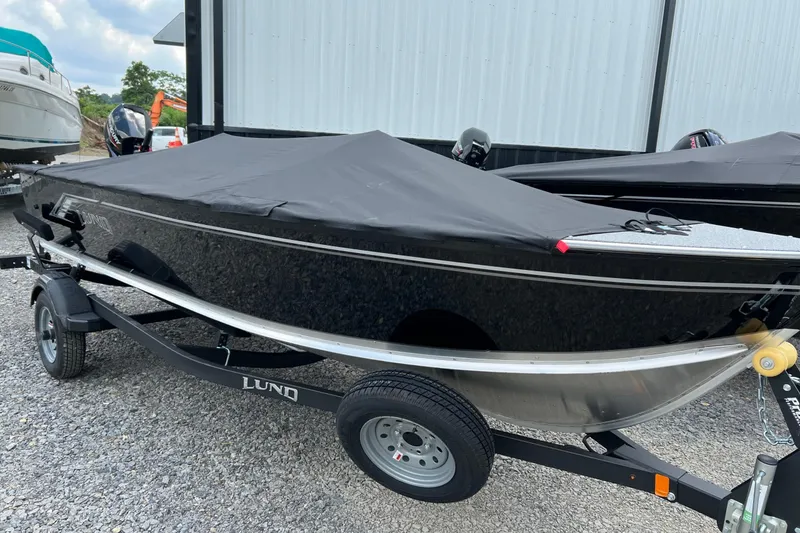 Slide: The Image of 2026 Lund 1600 Fury Tiller boat with cover on trailer, parked outdoors. - 1