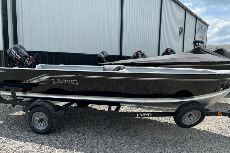 Slide: The Image of 2026 Lund 1600 Fury Tiller boat on trailer, parked outdoors. - 4