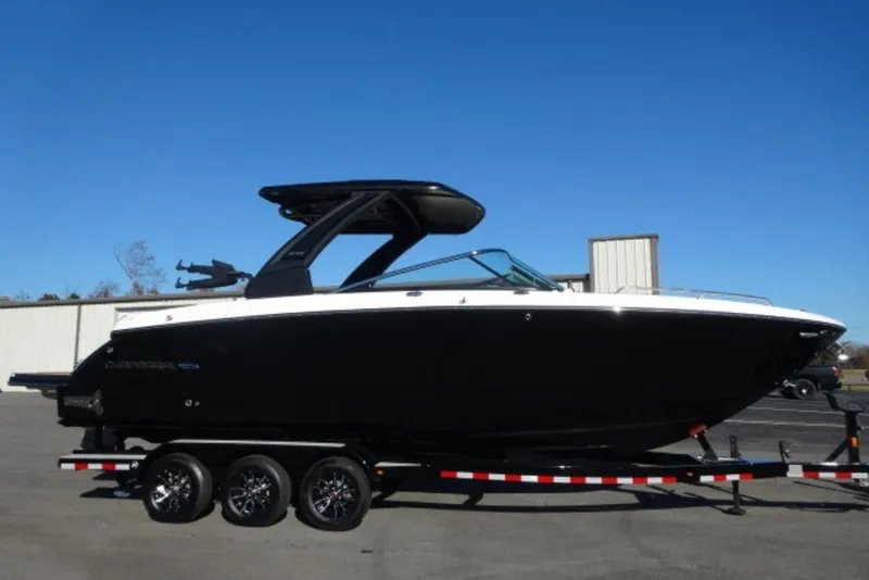 The Image of 2026 Chaparral 30 Surf boat on trailer, sleek black design under clear blue sky. - 2