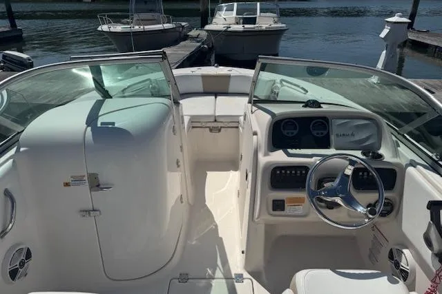 Slide: The Image of 2019 Robalo R207 Dual Console boat interior at dock, featuring steering wheel and seating. - 11