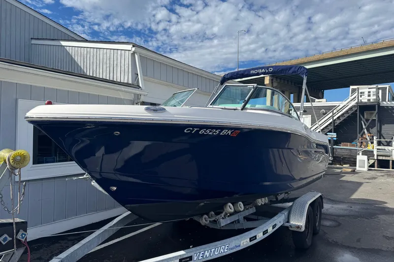Slide: The Image of 2019 Robalo R207 Dual Console boat on trailer, parked outdoors under a blue sky. - 22
