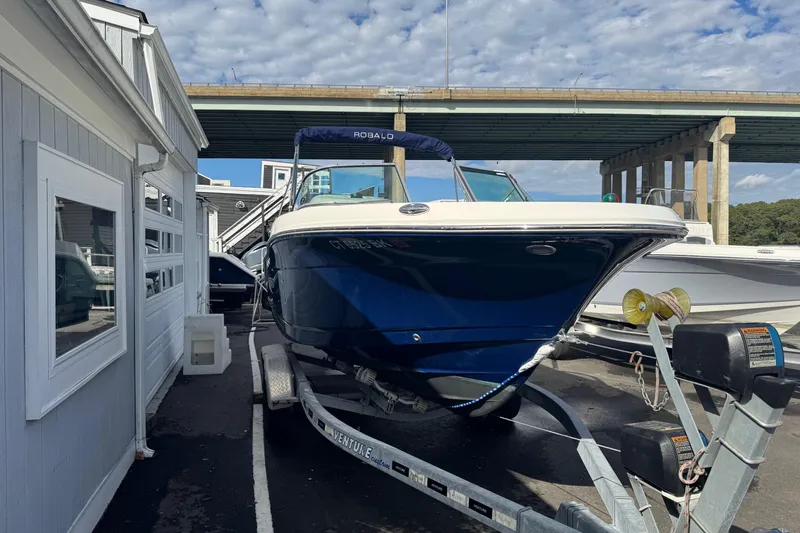 Slide: The Image of 2019 Robalo R207 Dual Console boat on trailer, parked near a building. - 23