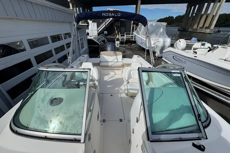 Slide: The Image of 2019 Robalo R207 Dual Console boat docked under a bridge, featuring spacious seating. - 26