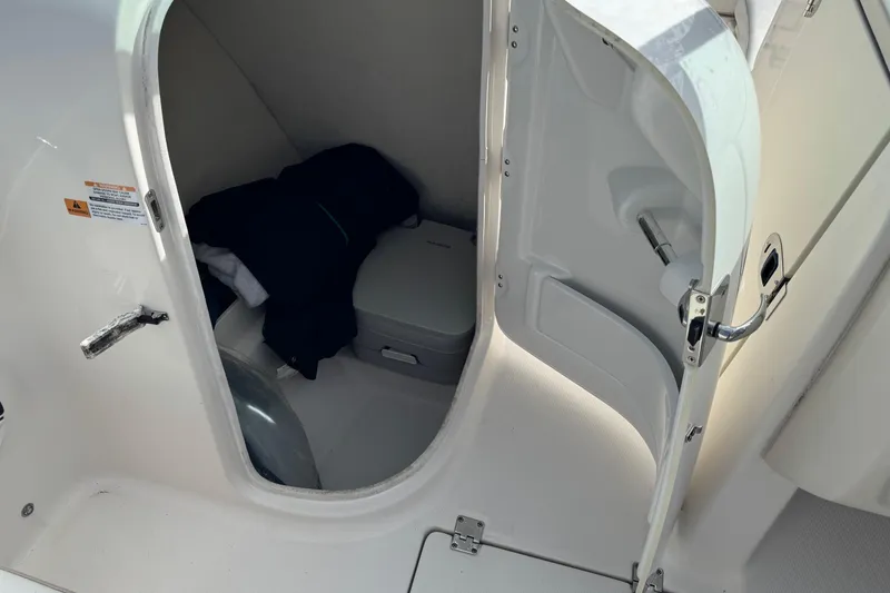 Slide: The Image of 2019 Robalo R207 Dual Console boat storage compartment with clothing and portable toilet. - 32