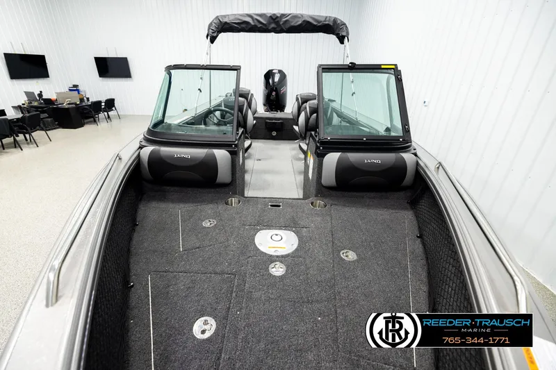 Slide: The Image of 2026 Lund 1975 Tyee boat interior with seating and dashboard, displayed in showroom. - 16