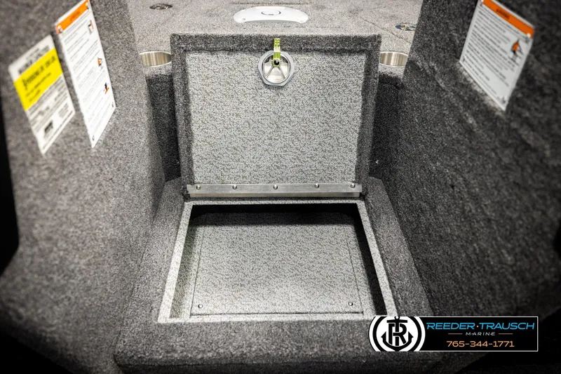 Slide: The Image of Open storage compartment in 2026 Lund 1975 Tyee boat, featuring carpeted interior and safety labels. - 31