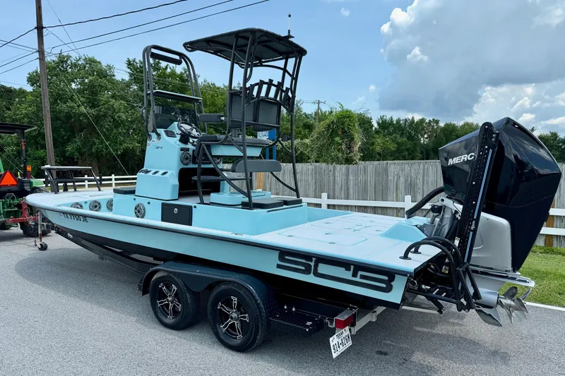 Slide: The Image of 2020 SCB R24 boat on trailer with Mercury engine, parked on a street. - 2