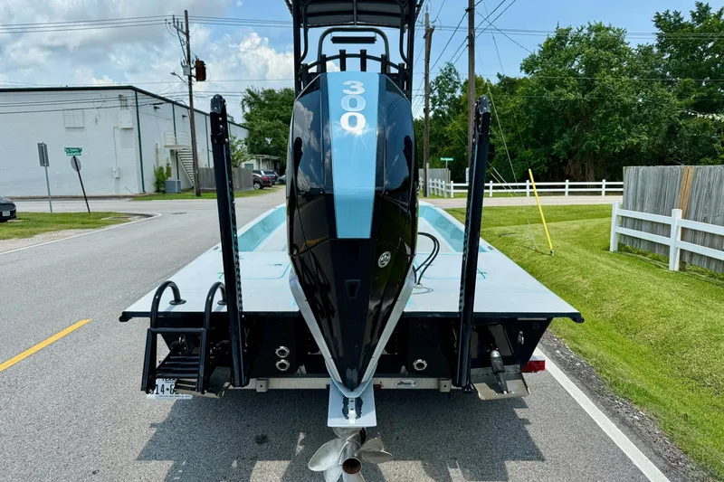 Slide: The Image of 2020 SCB R24 boat on trailer, rear view, parked on suburban street. - 3