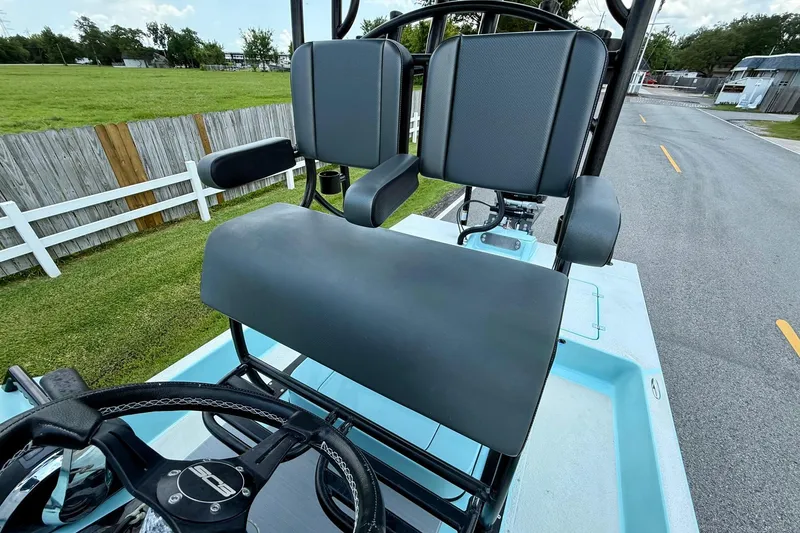 Slide: The Image of 2020 SCB R24 boat helm with dual seats and steering wheel, parked near a fence. - 9