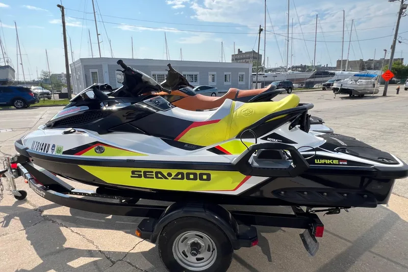 Slide: The Image of 2015 Sea-Doo Wake Pro 215 jet ski on trailer, parked near marina. - 2